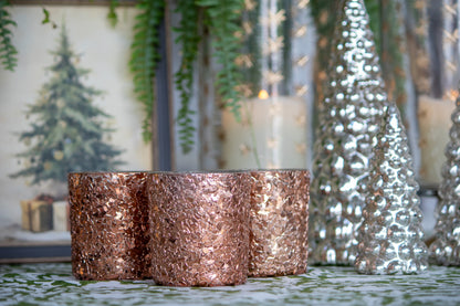 Rose gold candles with silver Christmas trees and lights in the background