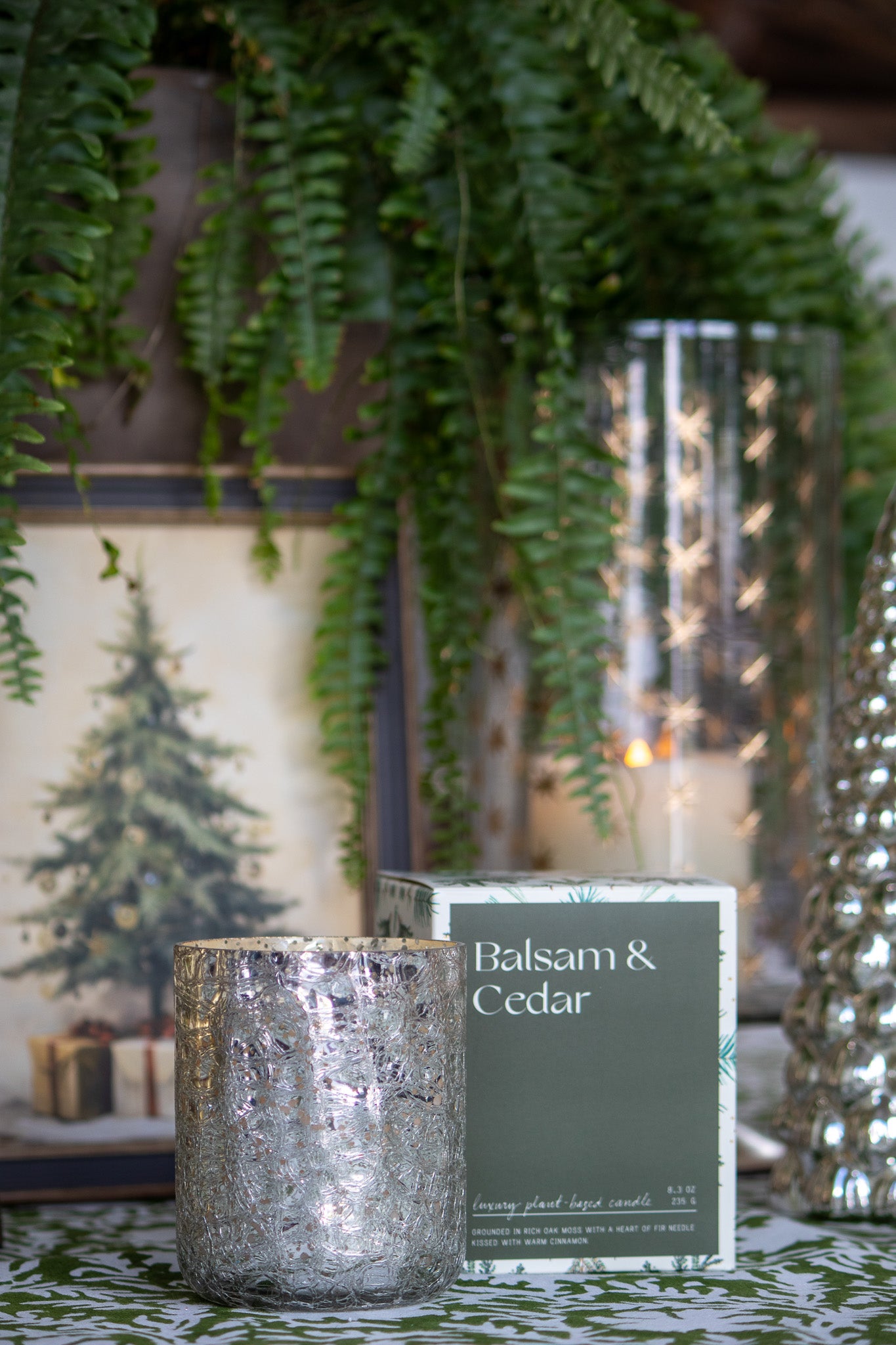 Decorative candle with 'Balsam & Cedar' label in front of a Christmas-themed background.