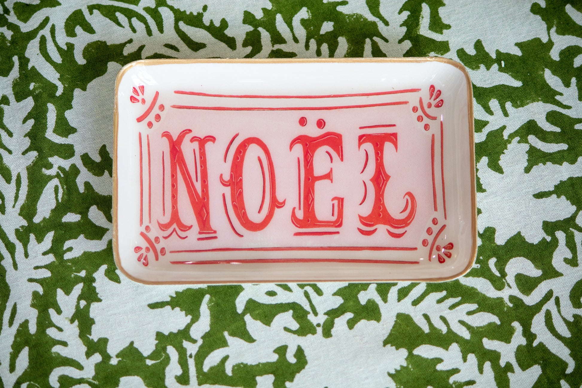 Decorative tray with 'NOEL' text on a green leafy tablecloth 