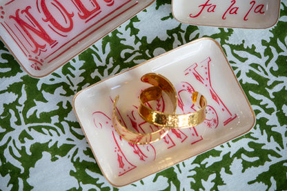 Gold bracelets  on a decorative plate with Christmas-themed text on a green and white patterned background