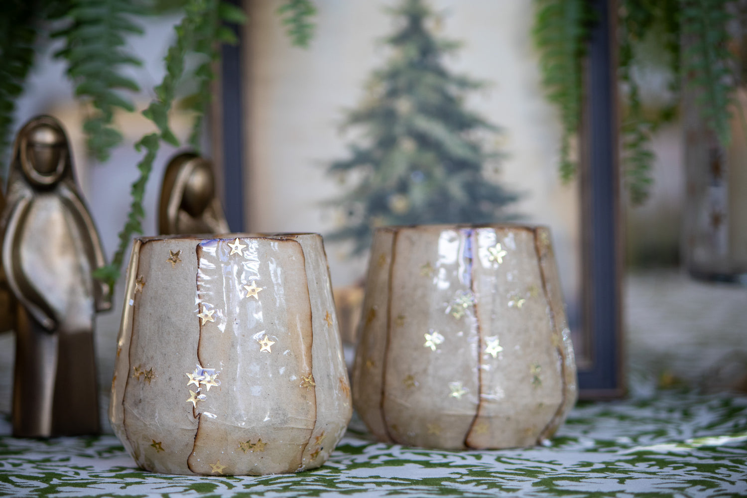 Two decorative glass candle holders with star patterns on a table with a blurred background