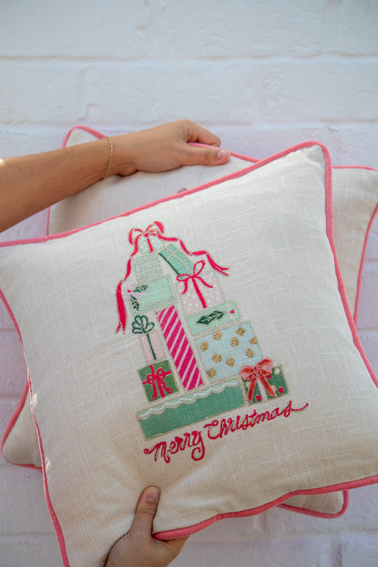 Decorative pillow with Christmas-themed embroidery held by a person on a white background
