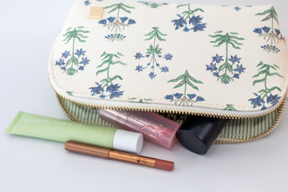 Makeup pouch with floral pattern containing makeup items on a white background