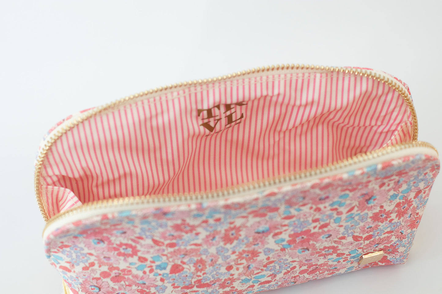 Floral patterned pouch with a pink interior on a white background