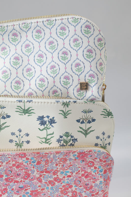 Three floral-patterned pouches stacked on a gray background