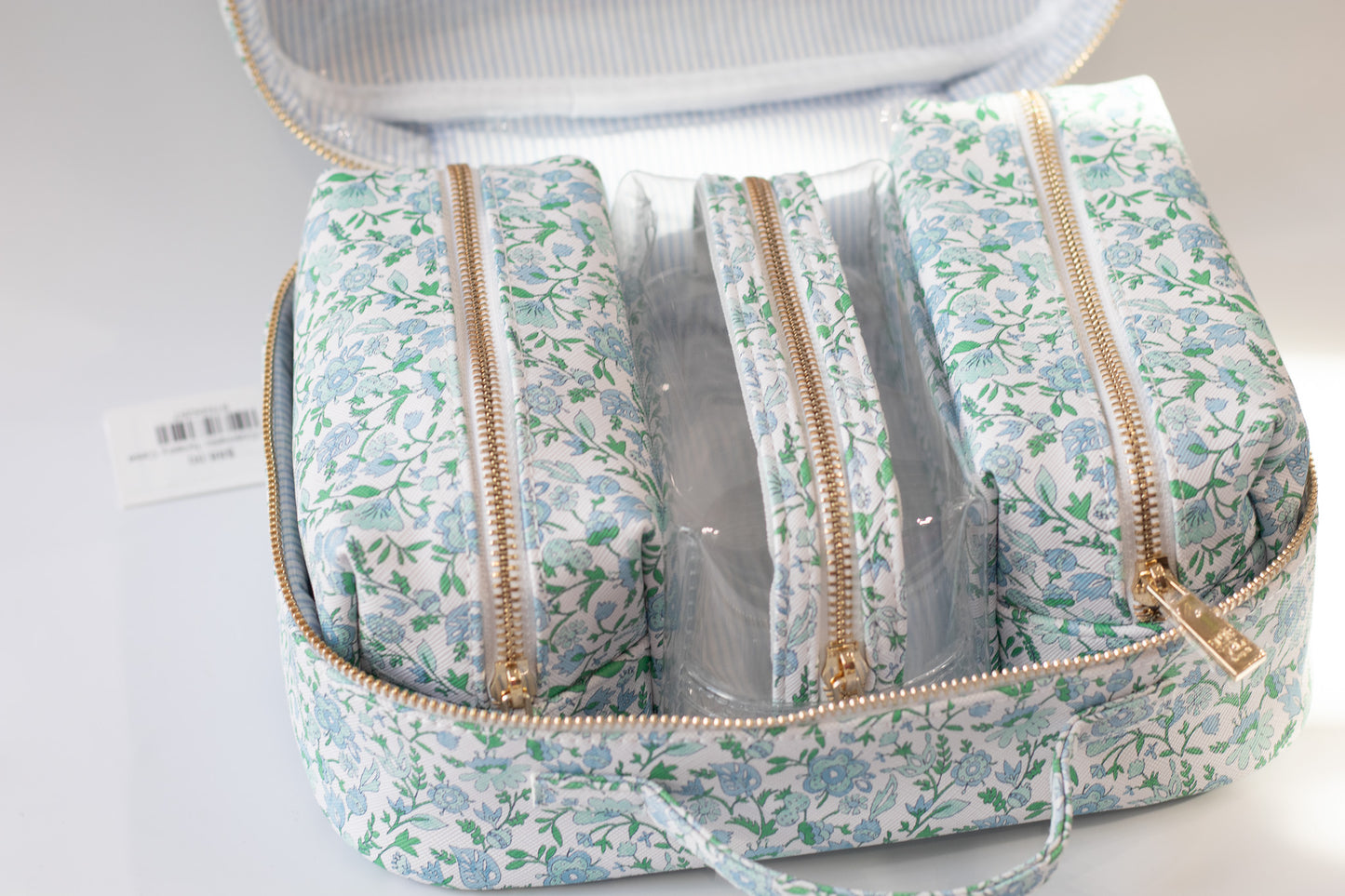 Floral-patterned toiletry bag with clear compartments on a white background