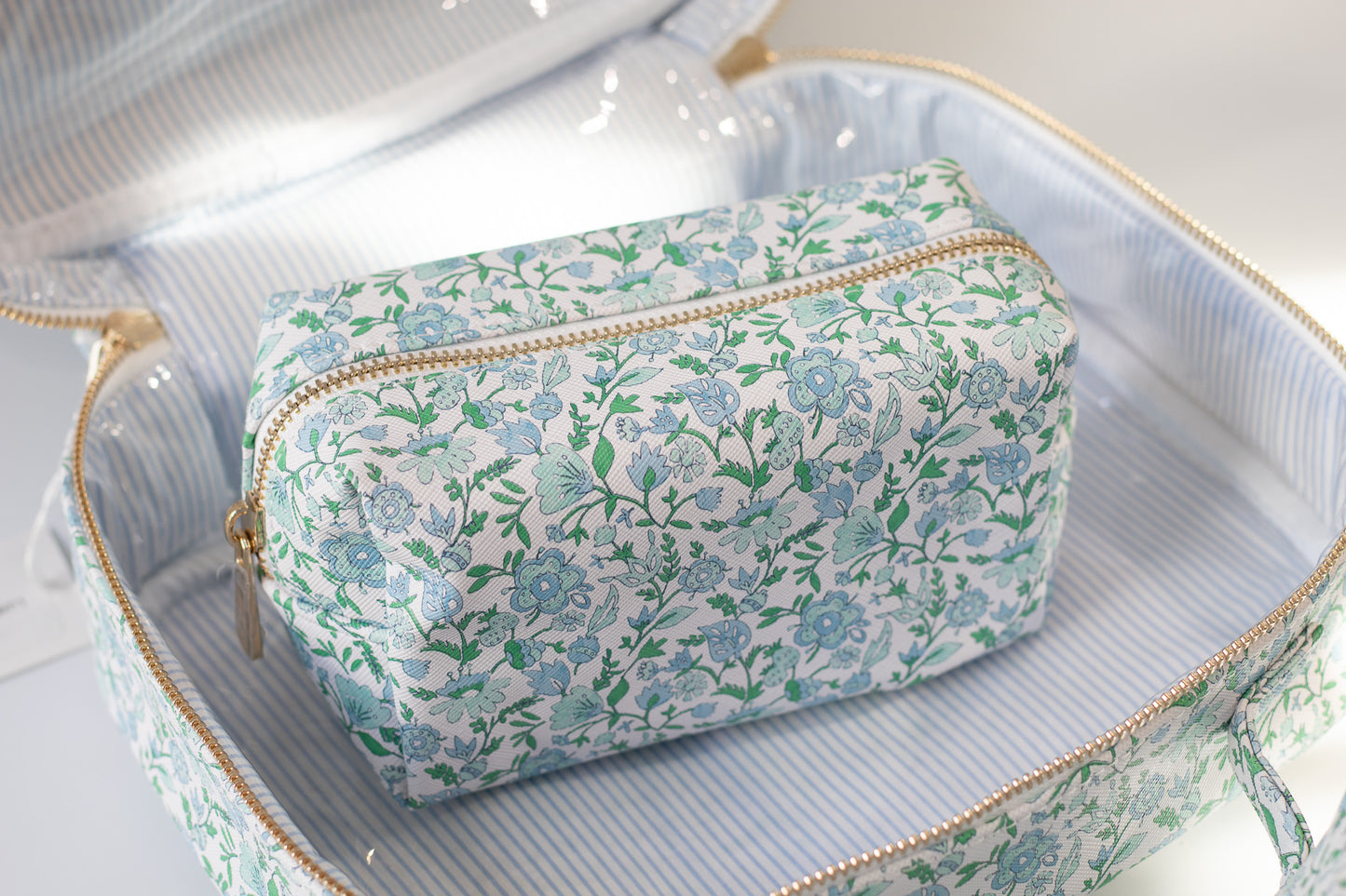 Floral-patterned toiletry bag inside an open bag on a light background