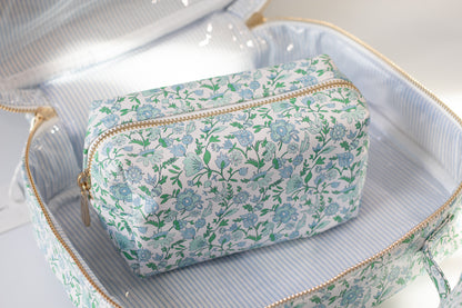 Floral-patterned toiletry bag inside an open bag on a light background