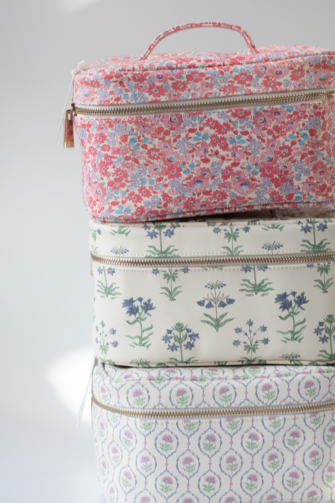 Stack of floral-patterned cosmetic bags on a light gray background