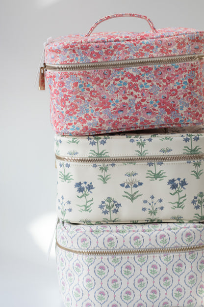 Stack of floral-patterned cosmetic bags on a light gray background