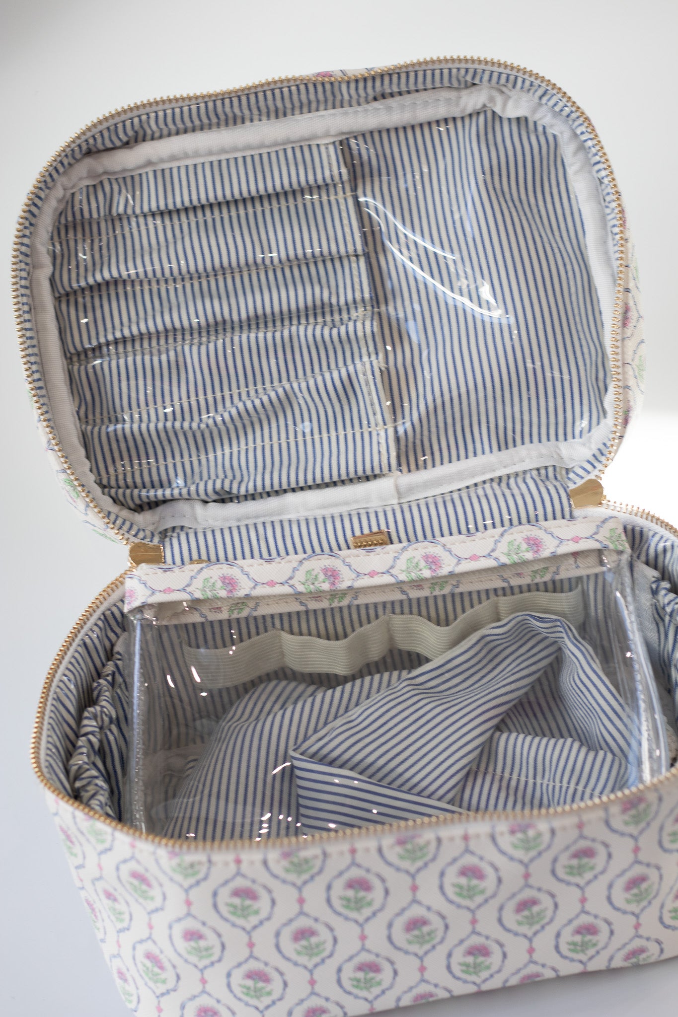 Open fabric suitcase with striped interior and floral exterior on a white background