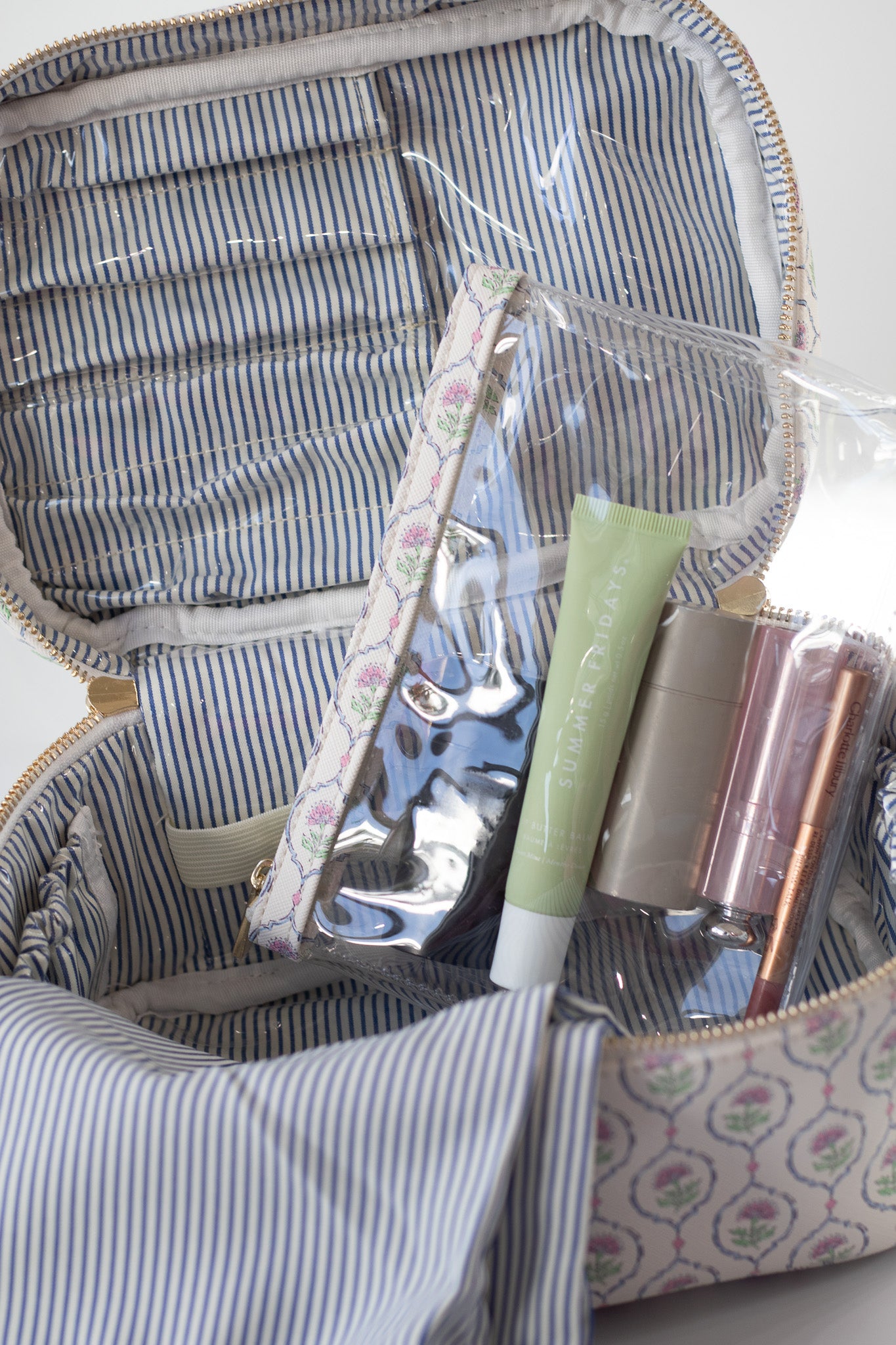 Clear plastic bag with makeup items inside a striped fabric container