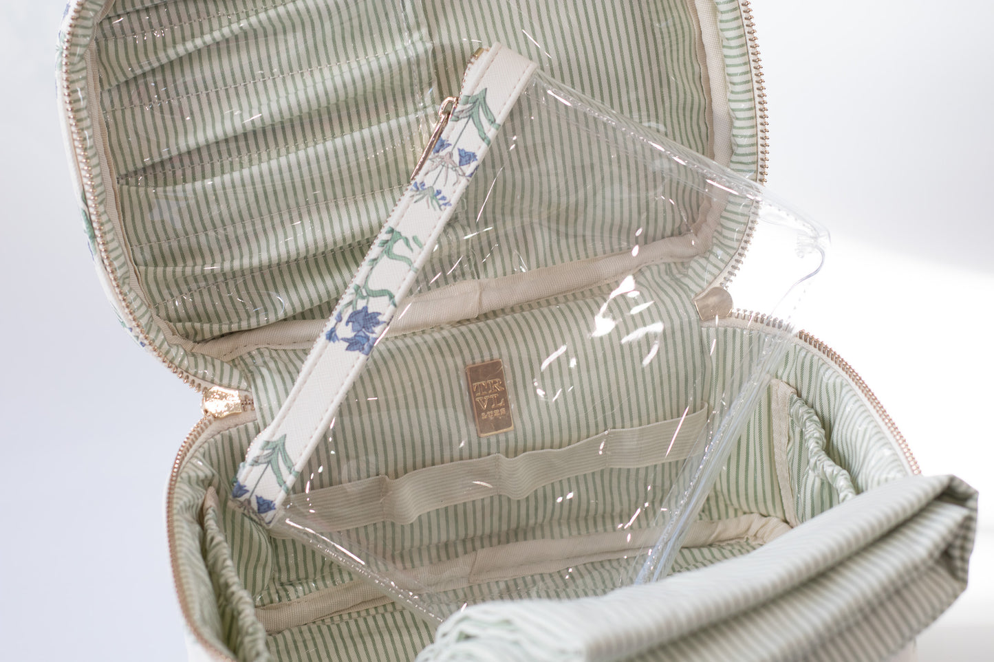 Open green striped makeup bag with clear plastic cover on a white background