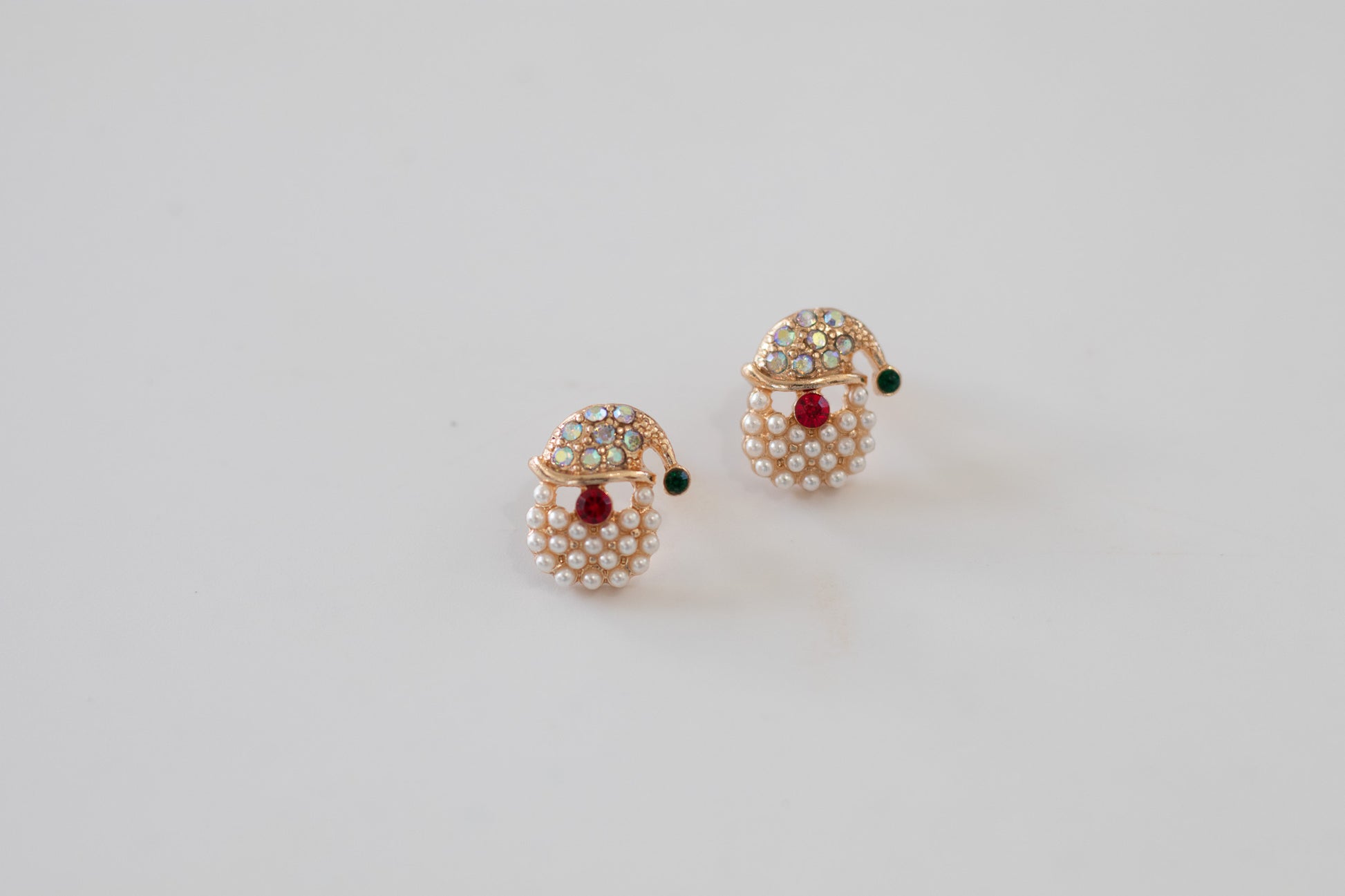 Pair of pearl santa earrings with red gemstones on a light gray background