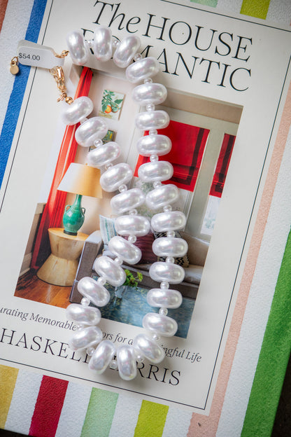 Pearl necklace on a magazine with a colorful striped background