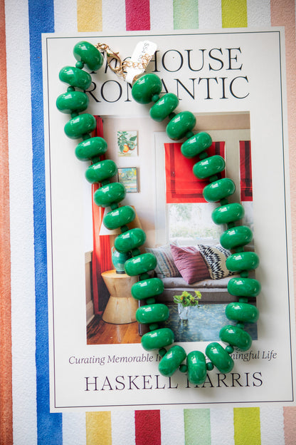 Green beaded necklace on a magazine with a colorful striped background