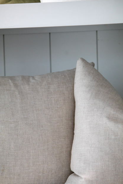 Two beige pillows on a white surface with a light gray wall in the background