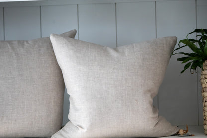 Two beige pillows on a surface with a neutral background