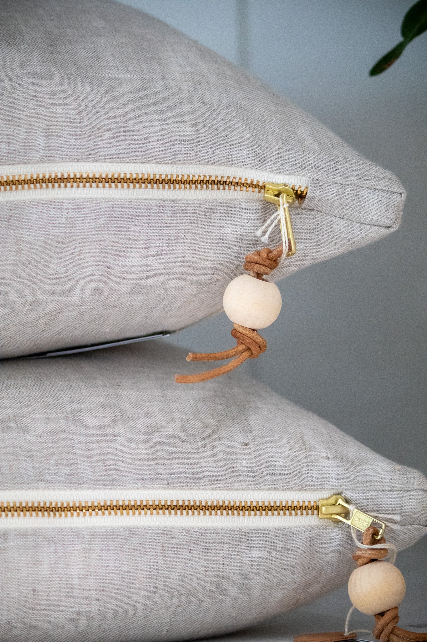 Gray pillows with gold zippers and decorative beads on a neutral background