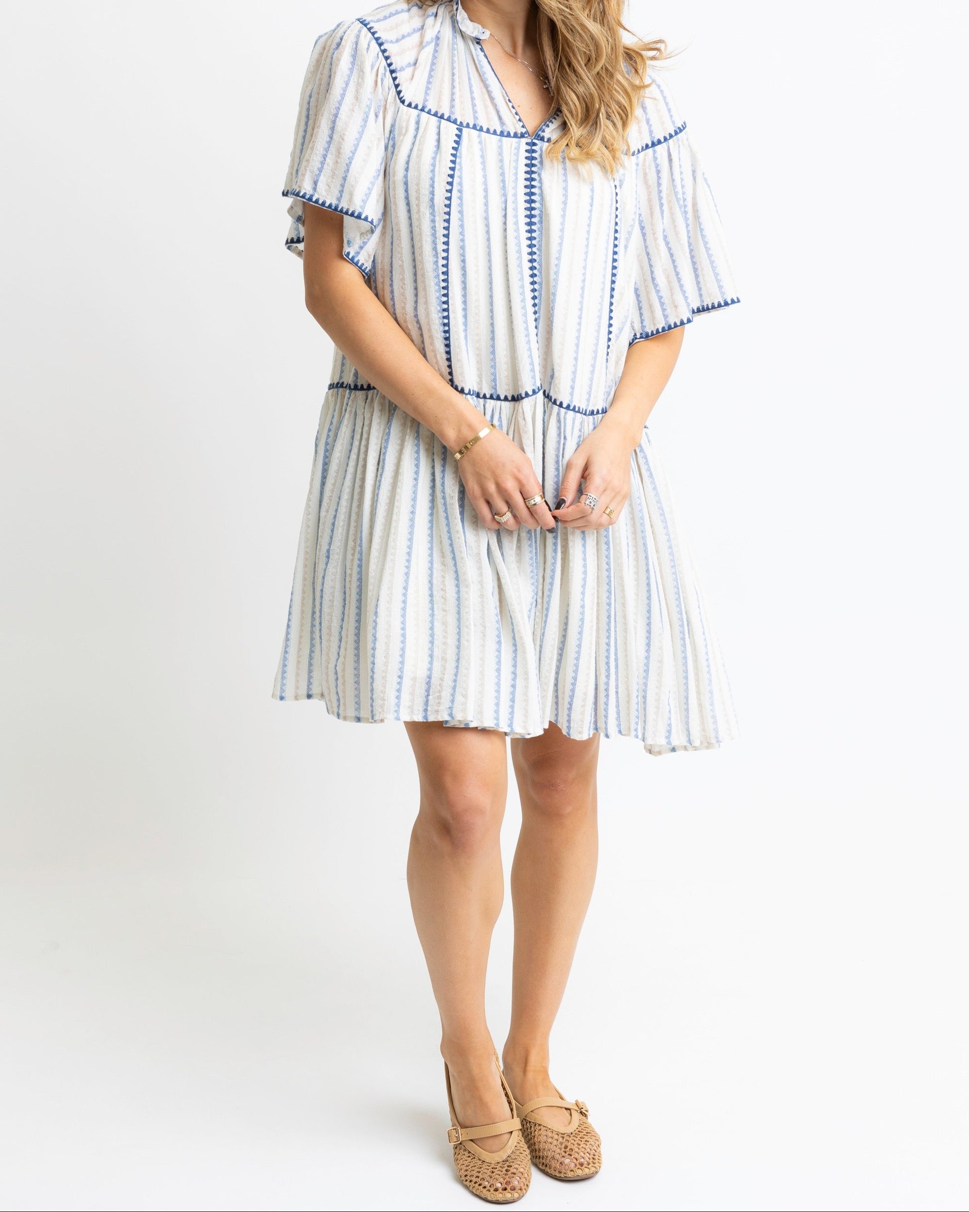 Woman wearing a white dress with blue stripes on a white background