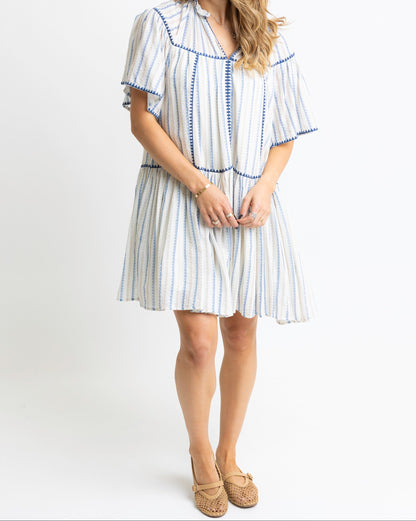Woman wearing a white dress with blue stripes on a white background