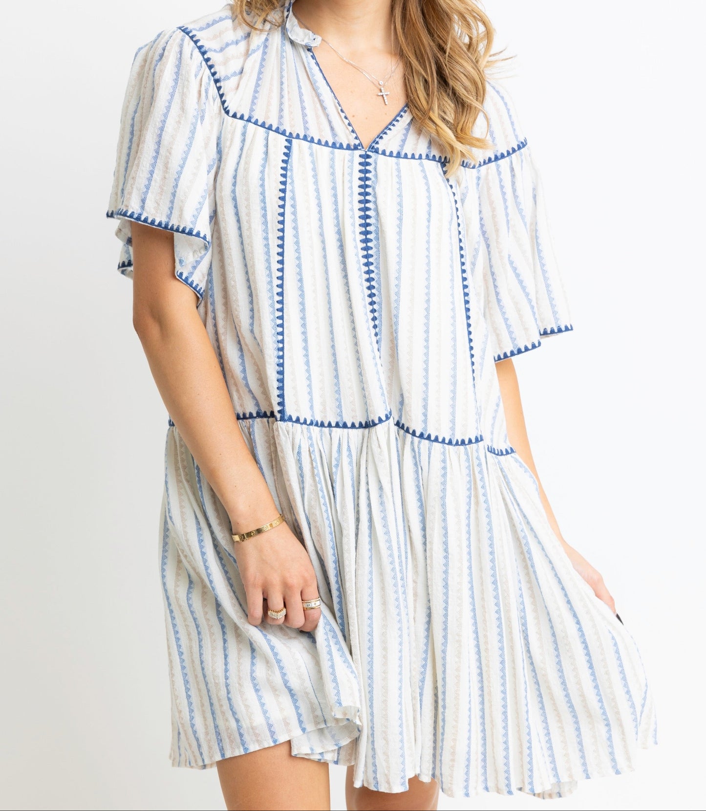 Woman wearing a white dress with blue stripes on a plain background