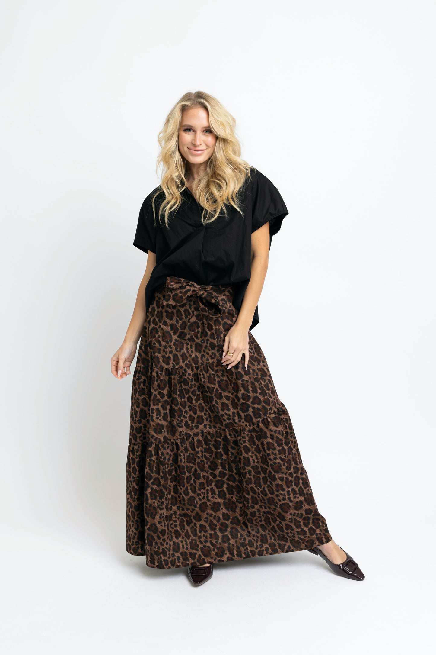 Woman wearing a black top and leopard print skirt on a white background
