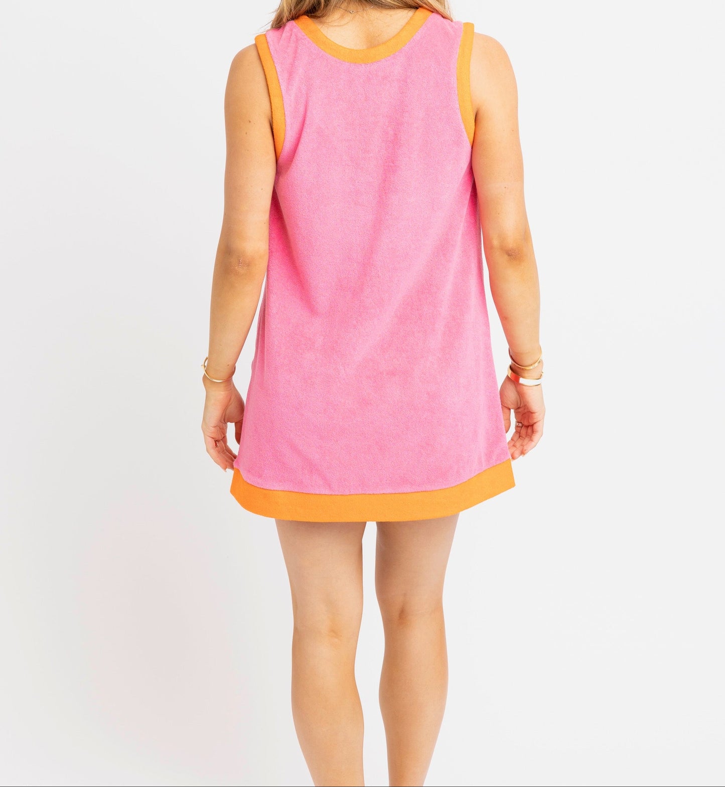 Woman wearing a pink sleeveless dress with an orange trim on a white background
