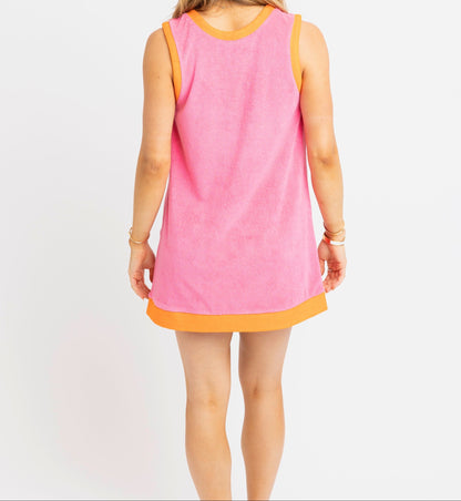 Woman wearing a pink sleeveless dress with an orange trim on a white background