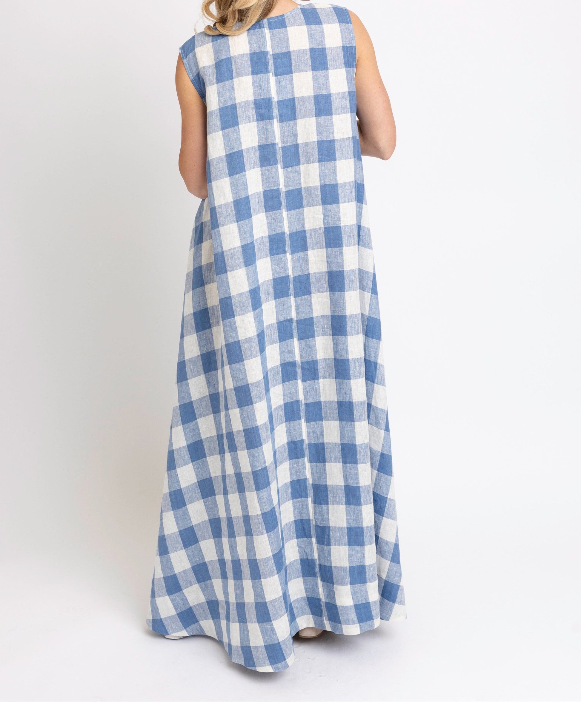 Woman wearing a blue and white checkered dress on a white background