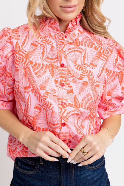Person wearing a pink and orange patterned shirt with a plain background