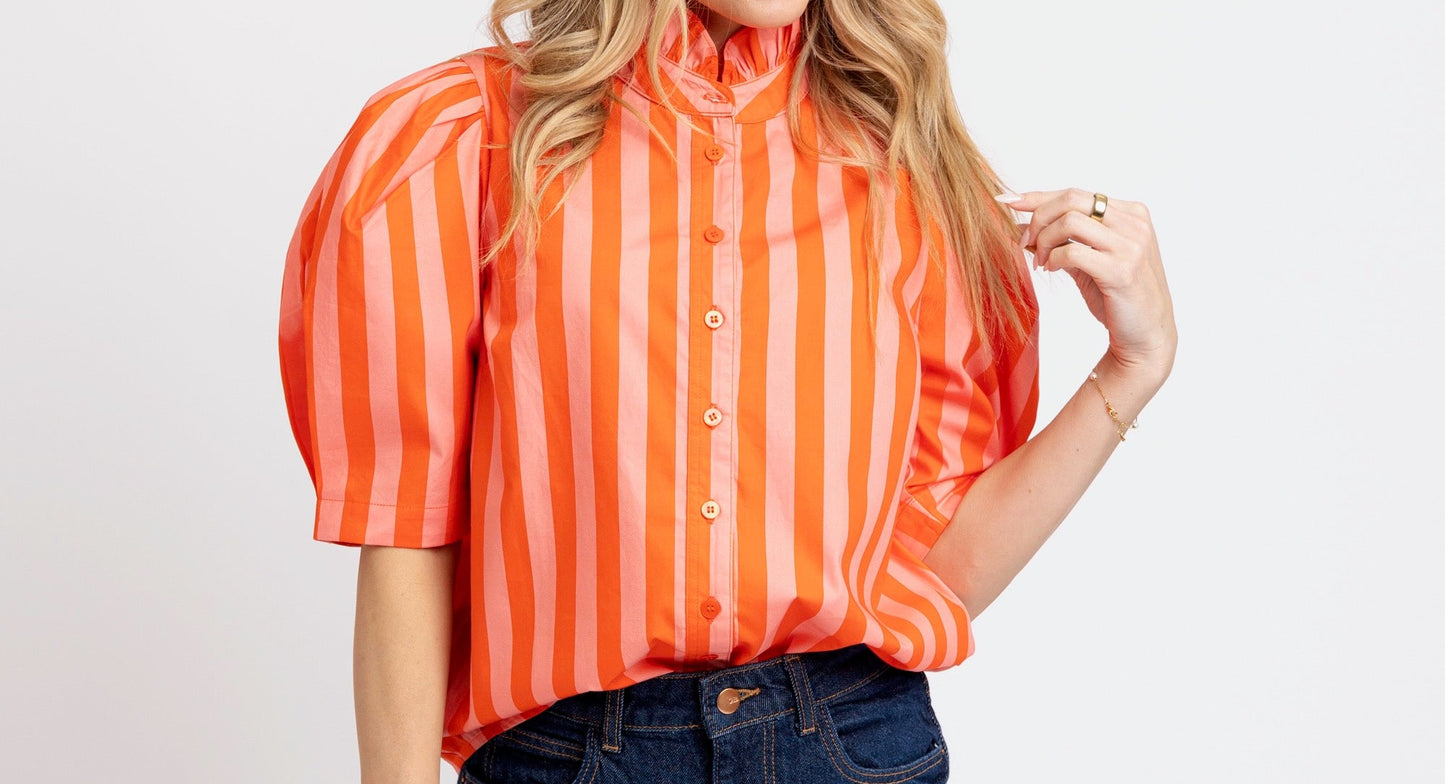 Woman wearing an orange striped shirt and blue shorts on a white background