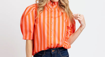 Woman wearing an orange striped shirt and blue shorts on a white background