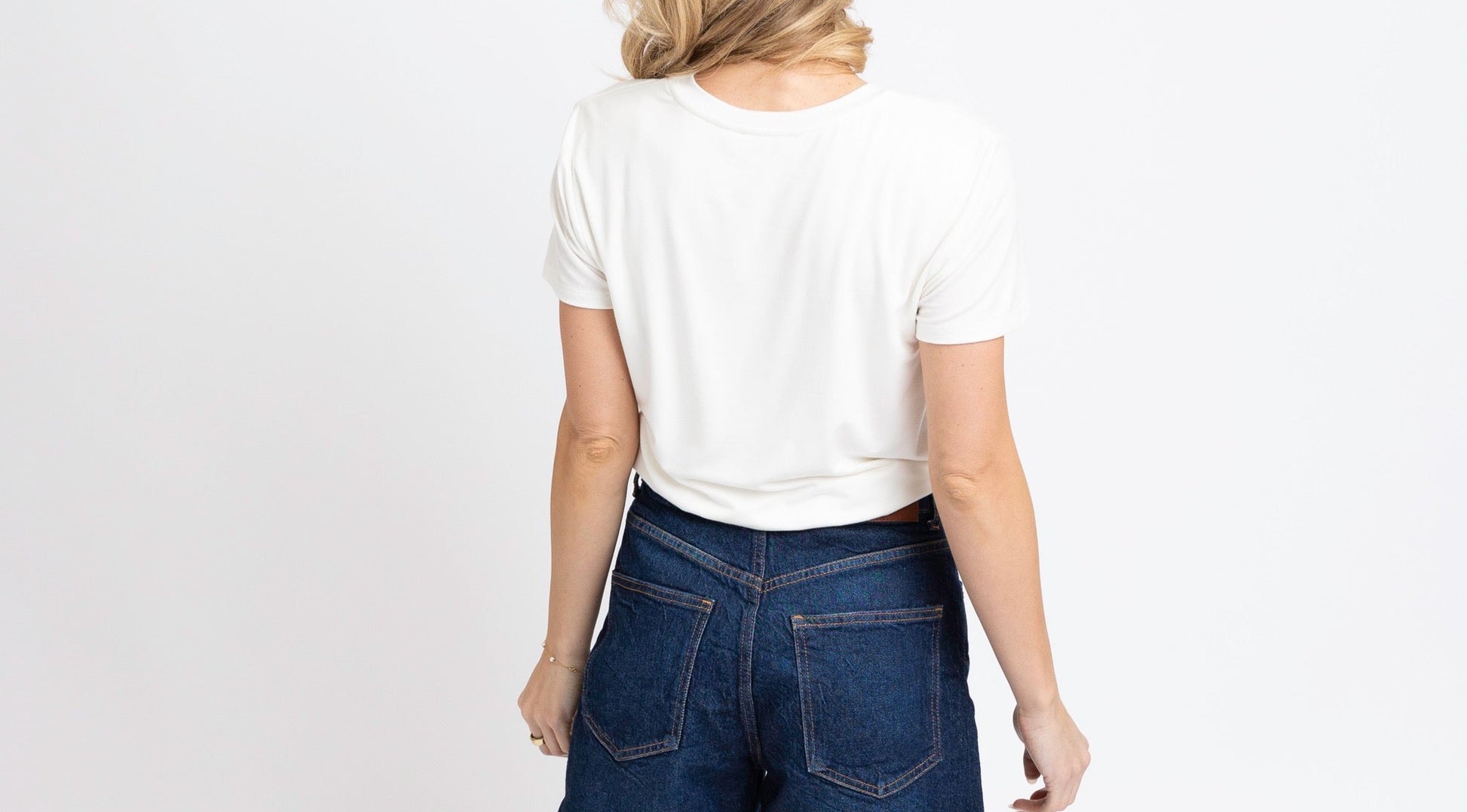 Person wearing blue denim shorts and a white t-shirt on a white background