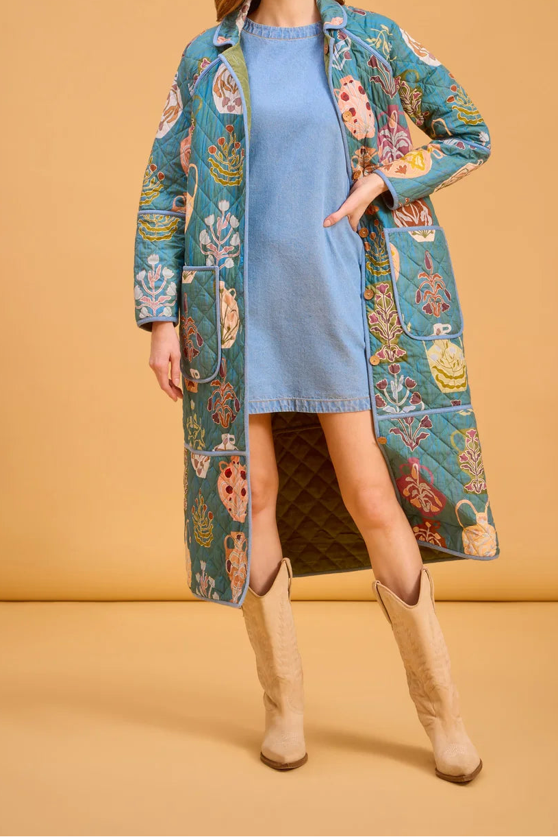 Woman wearing a long coat over a blue dress on a beige background