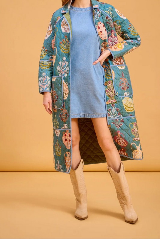 Woman wearing a long coat over a blue dress on a beige background
