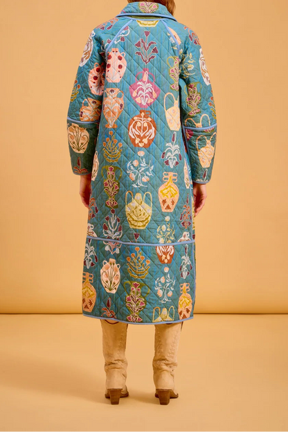Person wearing a colorful patterned coat against a beige background