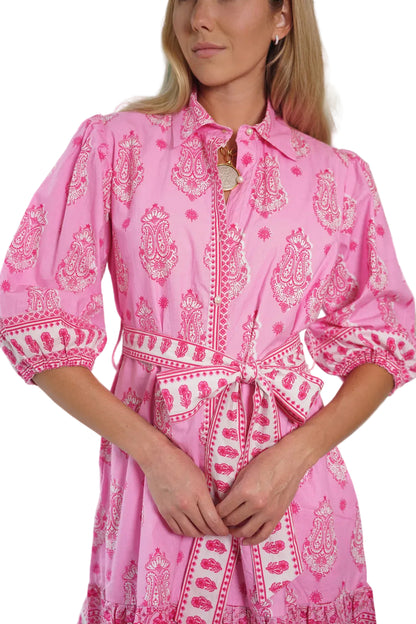 Woman wearing a pink patterned dress with a blurred outdoor background