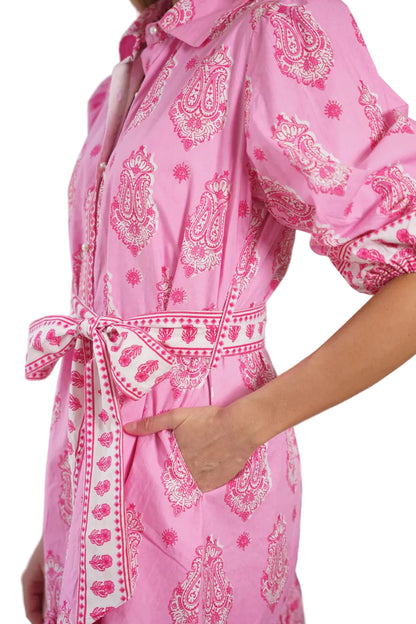 Person wearing a pink patterned dress with a blurred outdoor background