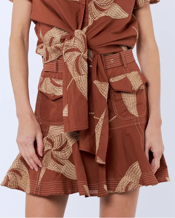 Woman wearing a brown dress with floral patterns on a white background