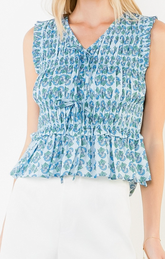 Woman wearing a blue floral sleeveless top and white skirt on a white background