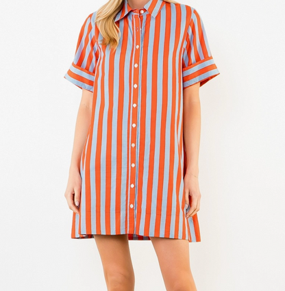 Person wearing an orange and blue striped shirt dress on a plain background