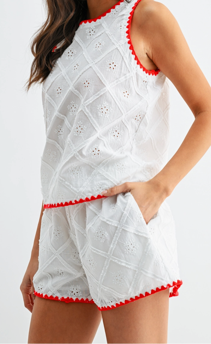 Woman wearing a white outfit with red trim on a white background