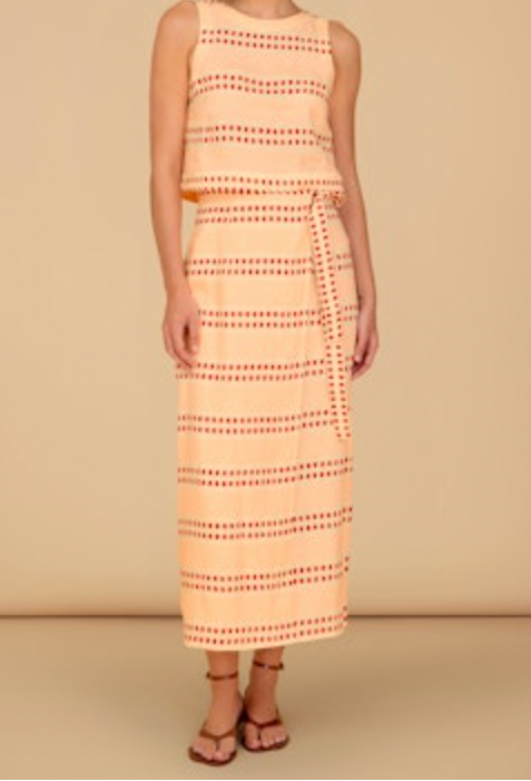 Woman wearing a sleeveless top and skirt with a pattern on a beige background