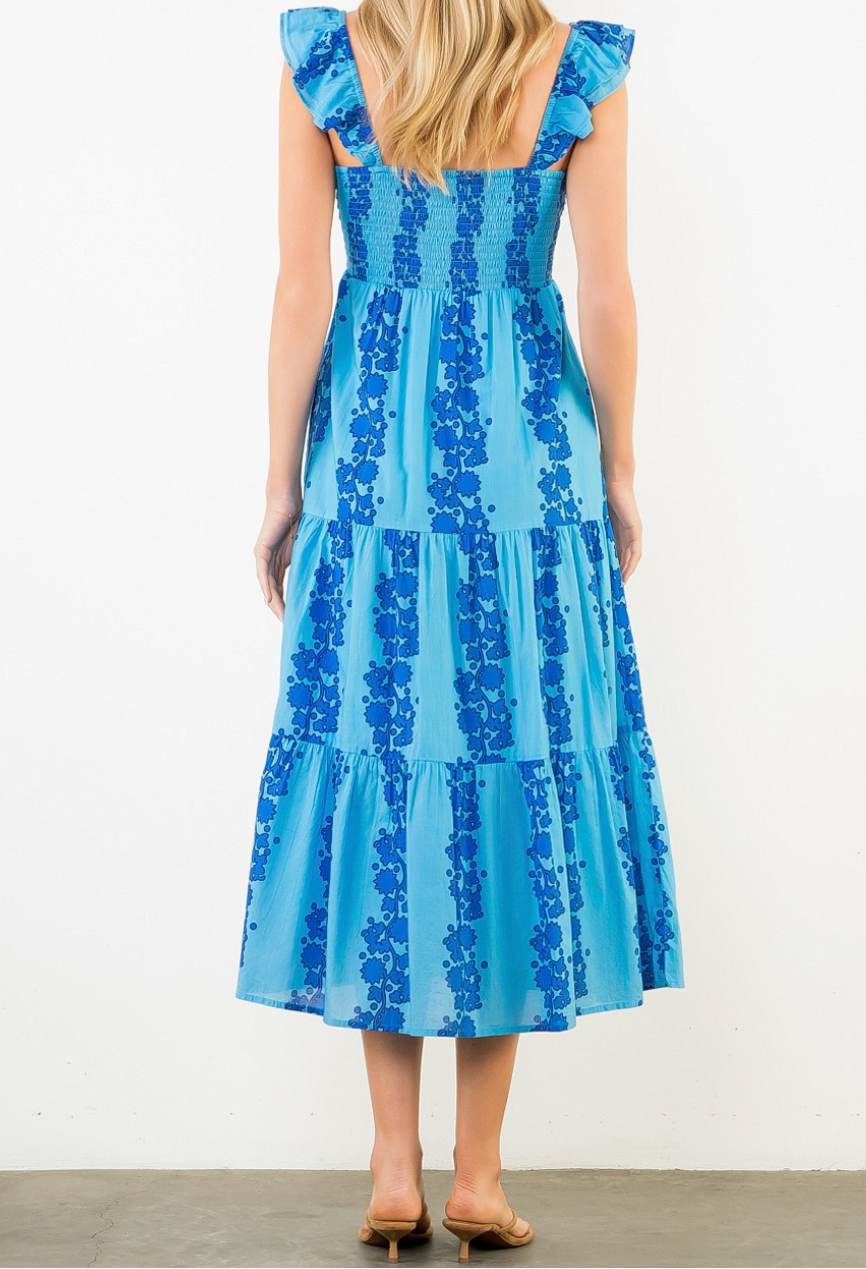 Woman wearing a blue dress with floral pattern against a white background