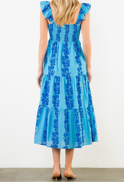 Woman wearing a blue dress with floral pattern against a white background