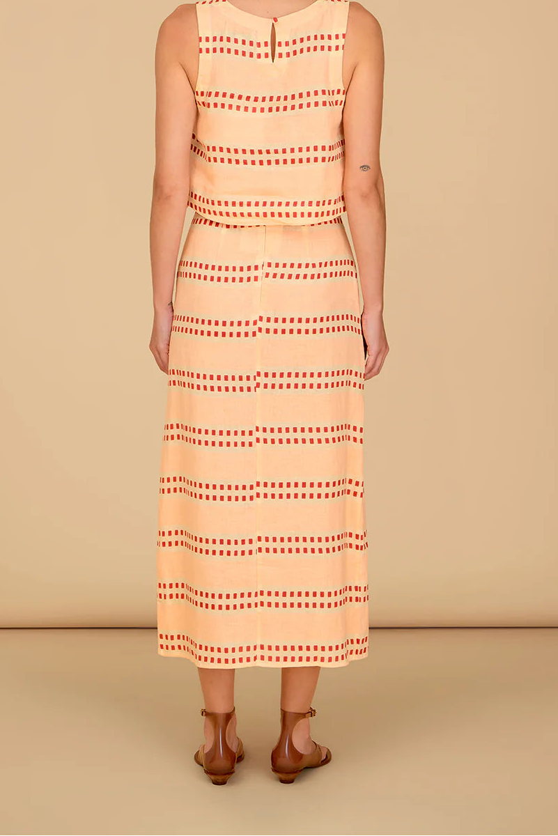 Woman wearing a sleeveless dress with a geometric pattern on a beige background