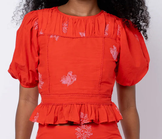 Woman wearing a red dress with white patterns against a white background