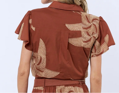 Woman wearing a brown dress with floral patterns on a white background