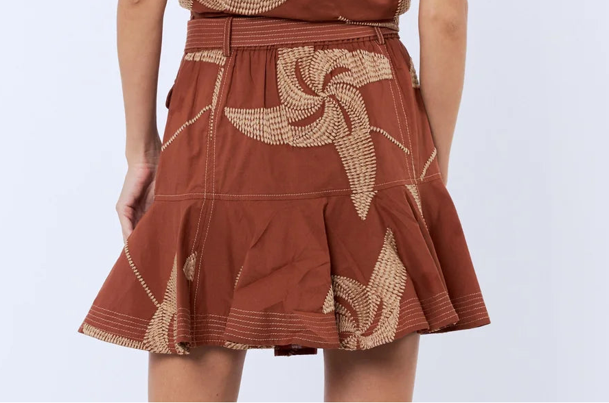 Woman wearing a brown dress with floral patterns on a white background